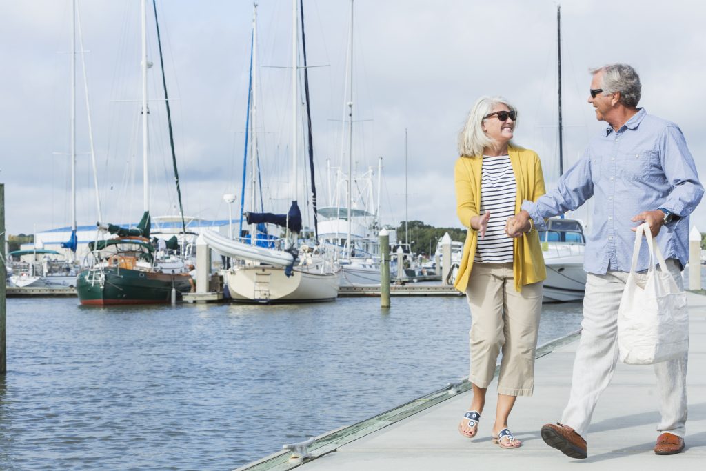 Podiatrists | Happy senior couple walking along harbor holding hands Podiatrists | Advanced Health Medical Centre | Bankstown